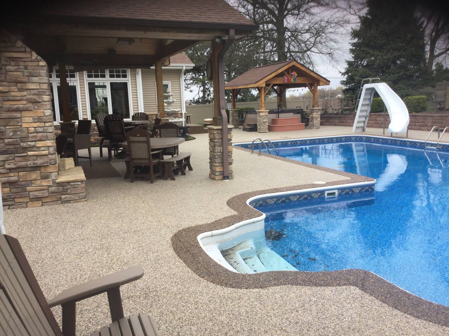 A pool with a slide and a gazebo in the background.